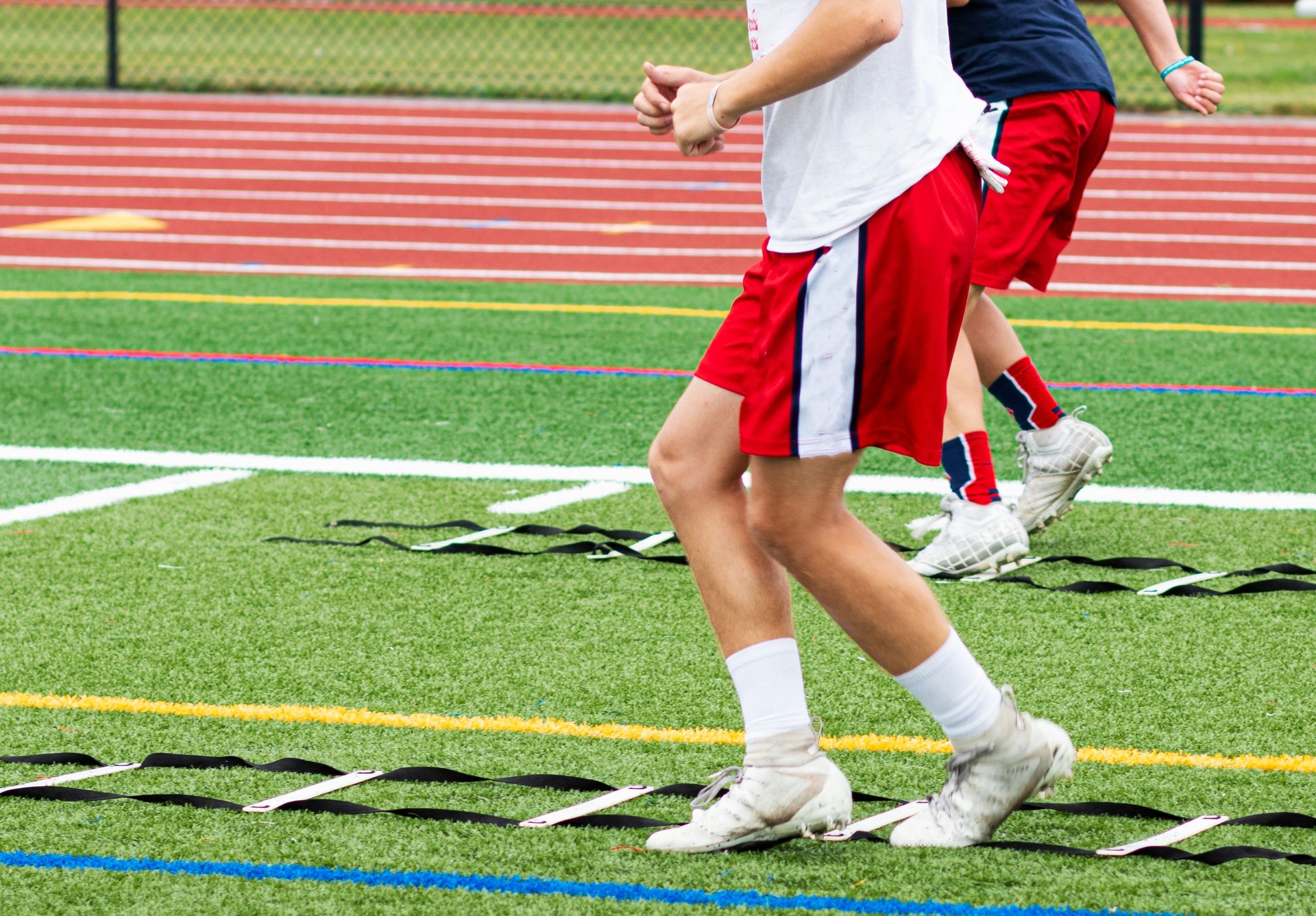 Athletes running ladder drills on a green turf field
